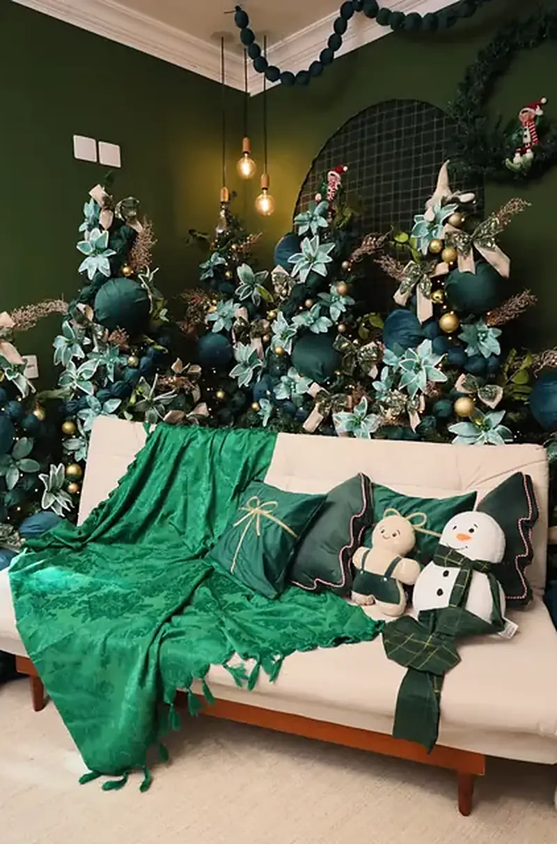 Estúdio Elegance decorado para o Natal, com sofá branco, manta verde, árvores em verde-esmeralda e renas brancas, na Mansão Eventual em São Paulo