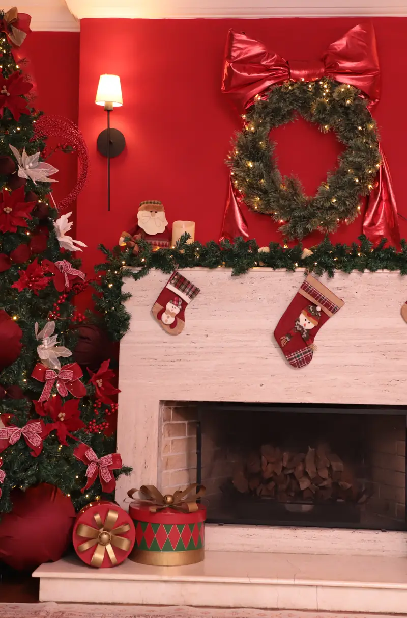 Loft Oásis decorado para o Natal, com paredes vermelhas, lareira com meias, guirlanda e árvores iluminadas, na Mansão Eventual em São Paulo